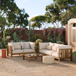 A stylish patio with black wicker chairs, a sofa, and a large umbrella.