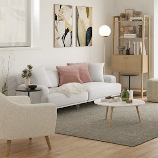 Modern living room with a light gray sofa, pink pillows, and wooden furniture.