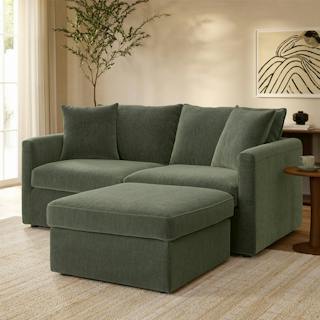 A green modular sofa in a modern living room with wooden walls and a dining set in the background.