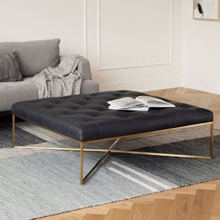 A cream bouclé storage ottoman with the lid open and a throw blanket draped over the side.