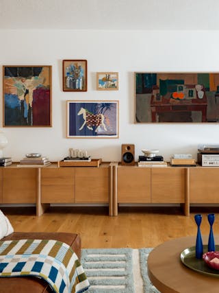 Modern living room with a wood sideboard, gallery wall, and cozy decor accents.