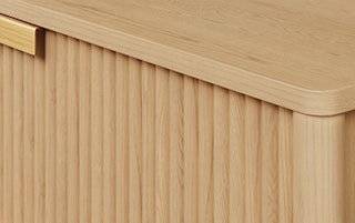 Close view of wood grain, fluted panels, and brass handles on Liv's cabinet panels