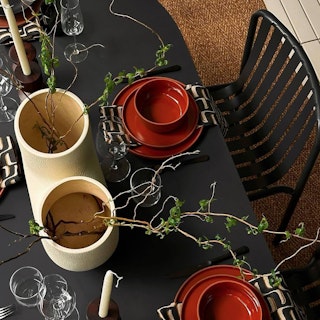 Moody dining table styled with the Sarek Outdoor Stackable Dining Chair in Black. Photo by @abhishekdekate