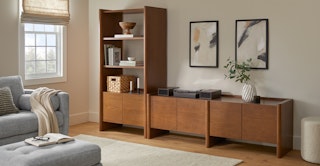 Torme 34" Tall Bookcase with Storage and 72" Media Unit in Smoked Oak finish, styled with art and books in a warm living room