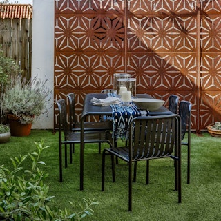 Lush, modern-industrial backyard, featuring Sarek steel Dining Table and Chairs in Black on a lawn. Photo by @mrorlandosoria