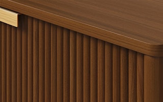 Close view of the brushed brass handles, fluted drawer fronts, and wood grain on the Liv Walnut collection