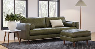 Warm mid-century modern living room featuring the Sven 88" Tufted Leather Sofa and Ottoman in Charme Green