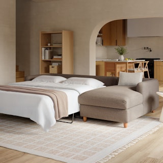 A brown sleeper right sectional sofa converted into a bed in a living room.