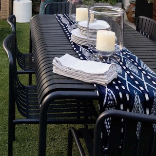 Styled image of the Sarek 67" Outdoor Dining Table and Stackable Dining Chairs in Black