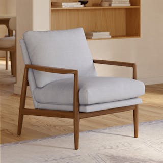 Mid-century modern light gray upholstered accent chair with a walnut wood frame in a living room.