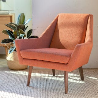An orange accent chair with wooden legs in a bright living room.