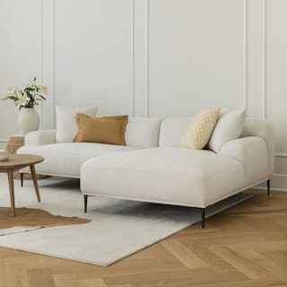 A white right sectional sofa with pillows in a light, minimal living room.