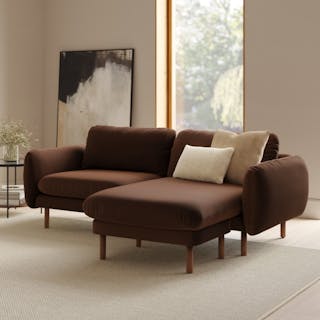A brown velvet sectional sofa with a reversible chaise in a bright living room.