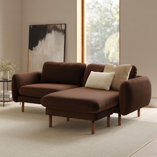 A brown velvet sectional sofa with a reversible chaise in a bright living room.