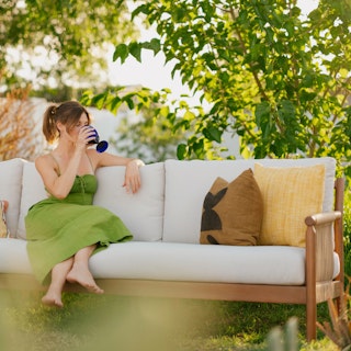 Person in a bright green dress sitting on the Rosa 110" Outdoor Sectional in Dravite Ivory. Photo by @nataliecarrasco_