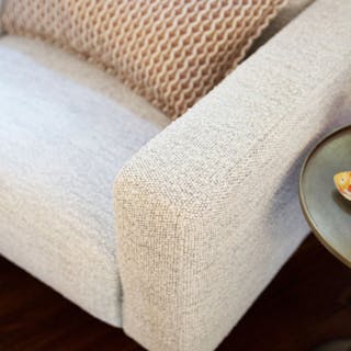 Close-up of an ivory textured fabric lounge chair arm. 