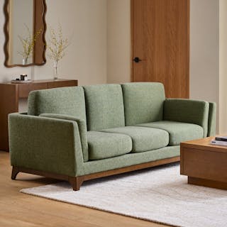 A green sofa in a warm, modern living room.