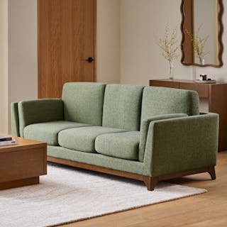 A green sofa in a warm, modern living room.